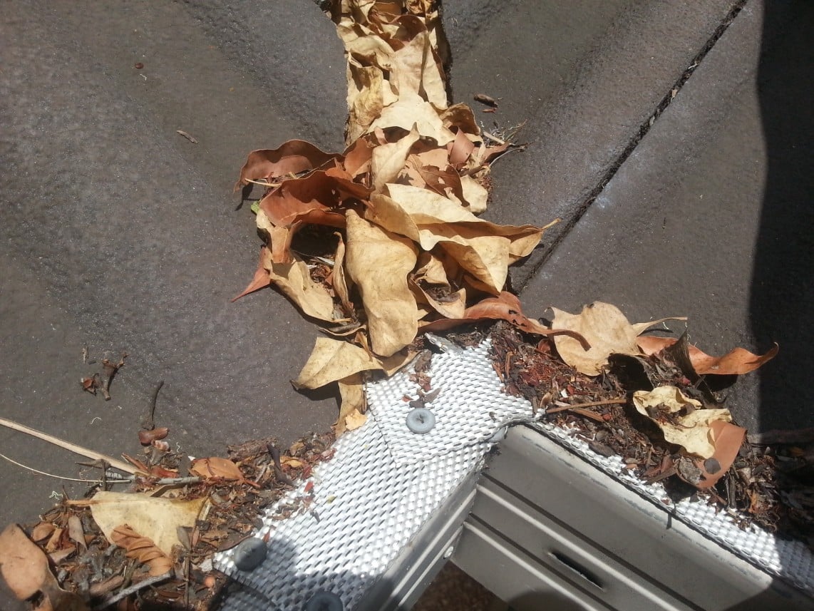 gutter inserted metal mesh blocked up causing water to cascade and back flow under valley