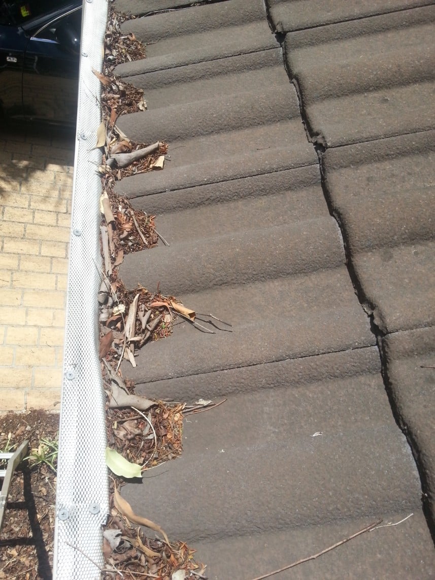 metal gutter guard blocked up on tiles allowing water to cascade over edge during rain